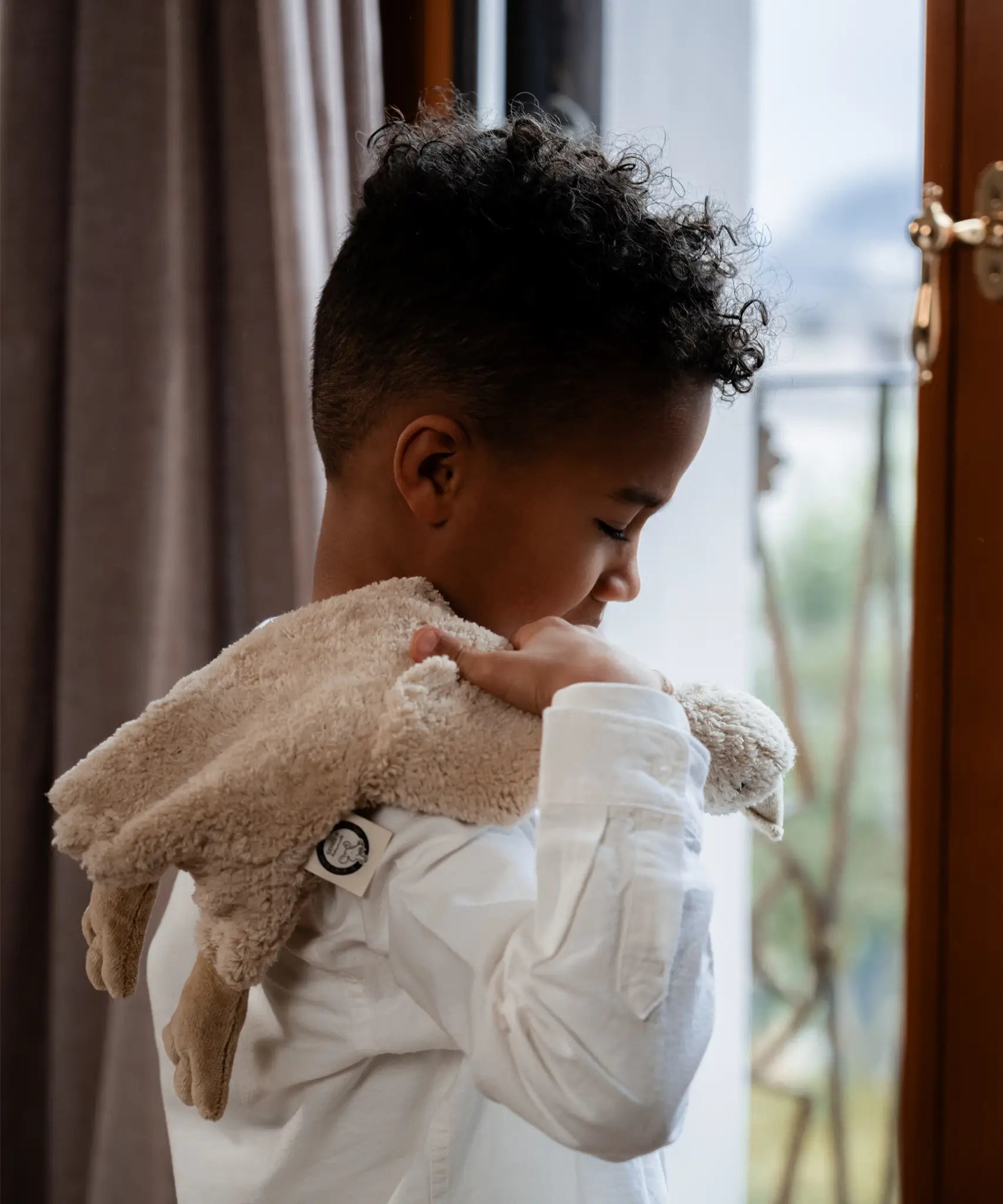 Child with a Senger GOTS organic cotton small cream cuddly goose soft toy over their shoulder 