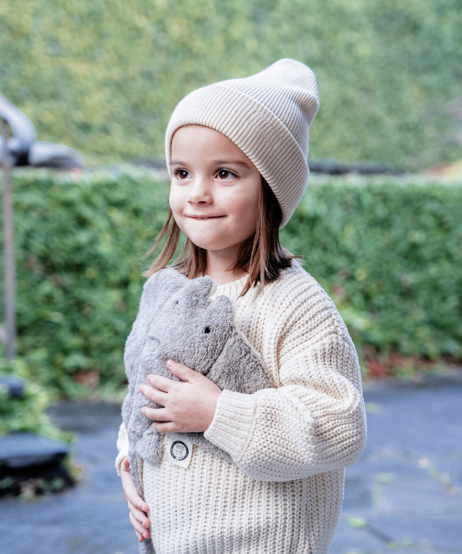 A little girl holding her Senger organic cotton heatable cuddly grey manta ray stuffed toy