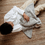 A view looking down on a little boy, cuddling the Senger large organic cotton grey manta ray heatable cuddly toy