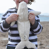 A child holding up the small Senger cuddly whale showing the white underside of the whale.