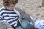 A child holding the small Senger whale cuddly animal up to their nose. 