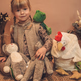 Child sitting next to a Senger baby cat, frog, elephant and a large cuddly chicken toy. 