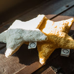 Two Senger star shaped warming cushions placed on the top of a trunk. One is a light yellow, off white colour and the other is a bright yellow colour. 