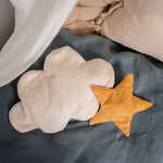 A yellow Senger star shaped warming cushion placed on a bed next to a white cloud cushion.