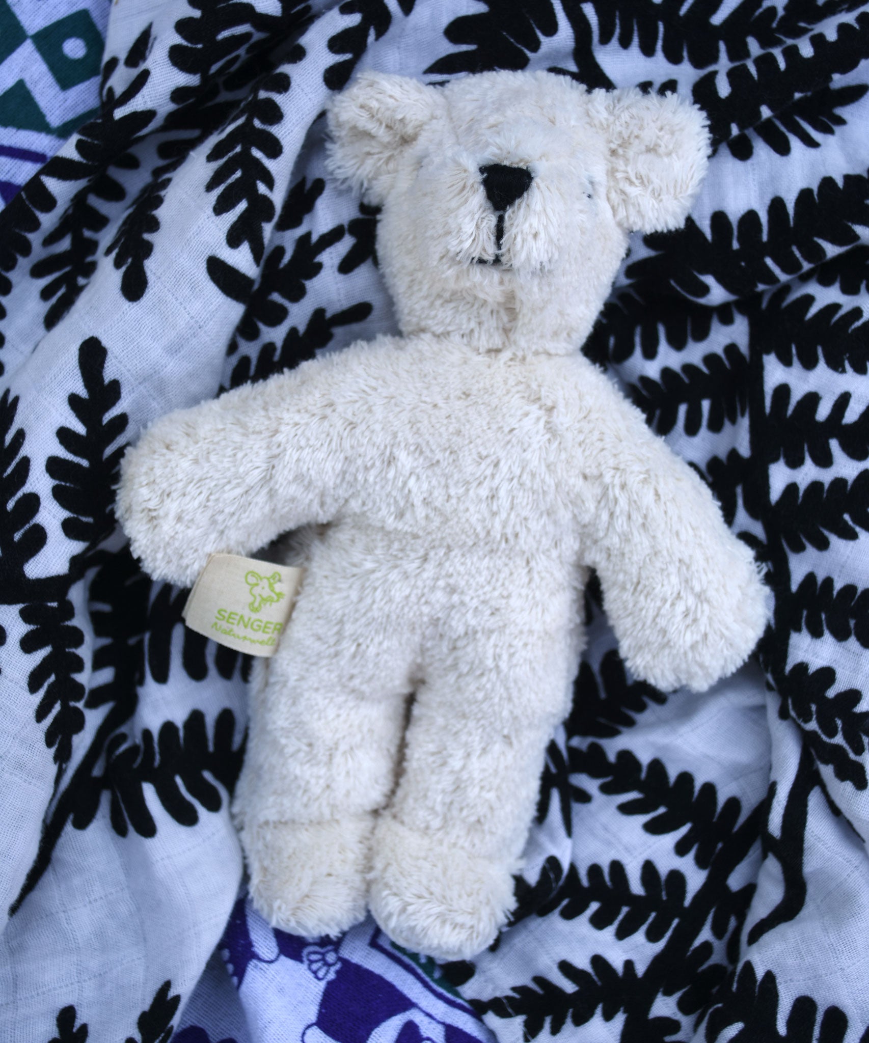  Senger white baby bear placed on an Etta Loves fern print sensory muslin cloth.