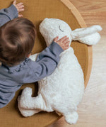 Child placing a hand on the Senger large white cuddly rabbit soft toy. Organic cotton outer with natural sheep's wool and spelt chaff filling.
