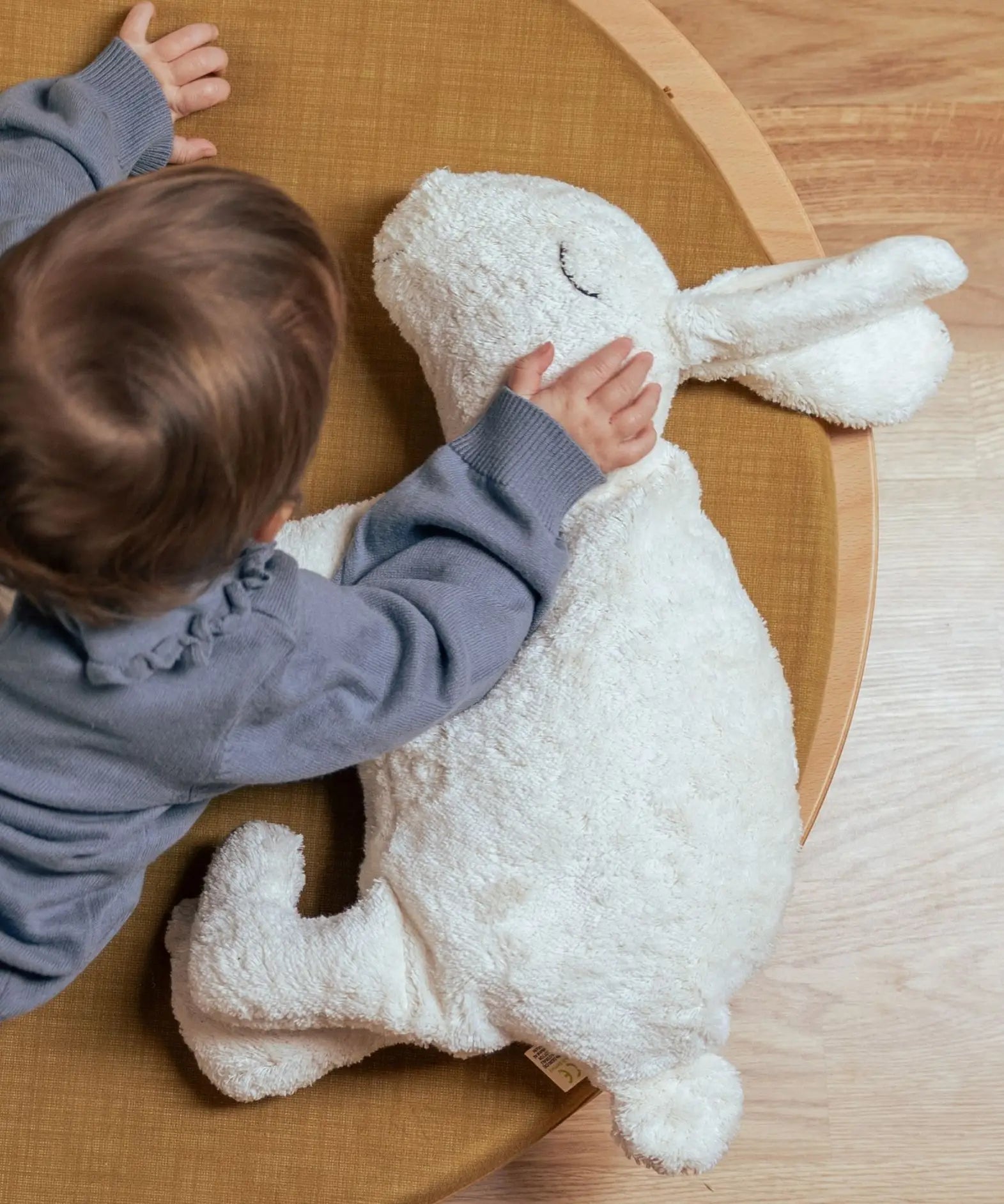 Child placing a hand on the Senger large white cuddly rabbit soft toy. Organic cotton outer with natural sheep's wool and spelt chaff filling.