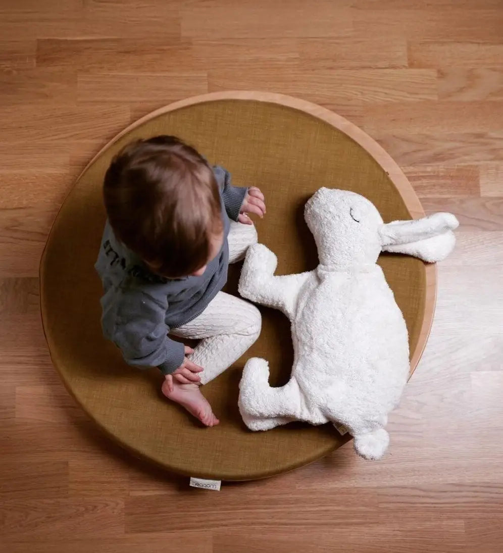 Child sitting on a wobbel 360 with deck with a Senger large white cuddly rabbit soft toy. 