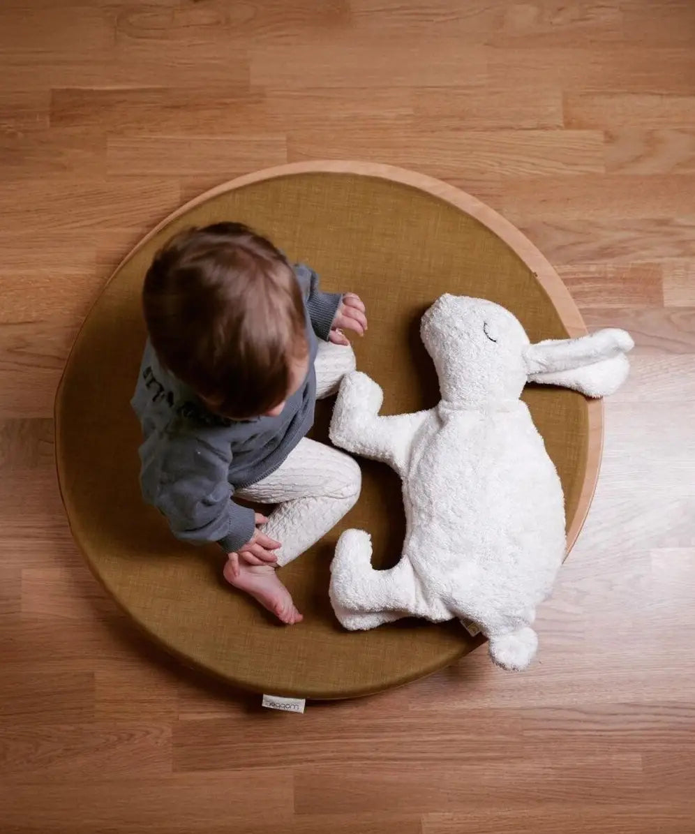 Child sitting on a wobbel 360 with deck with a Senger large white cuddly rabbit soft toy. 