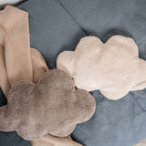 A white and grey cloud shaped Senger warming cushions placed on a bed. 