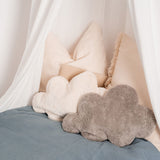 A white and grey cloud shaped Senger warming cushions placed on a bed. 