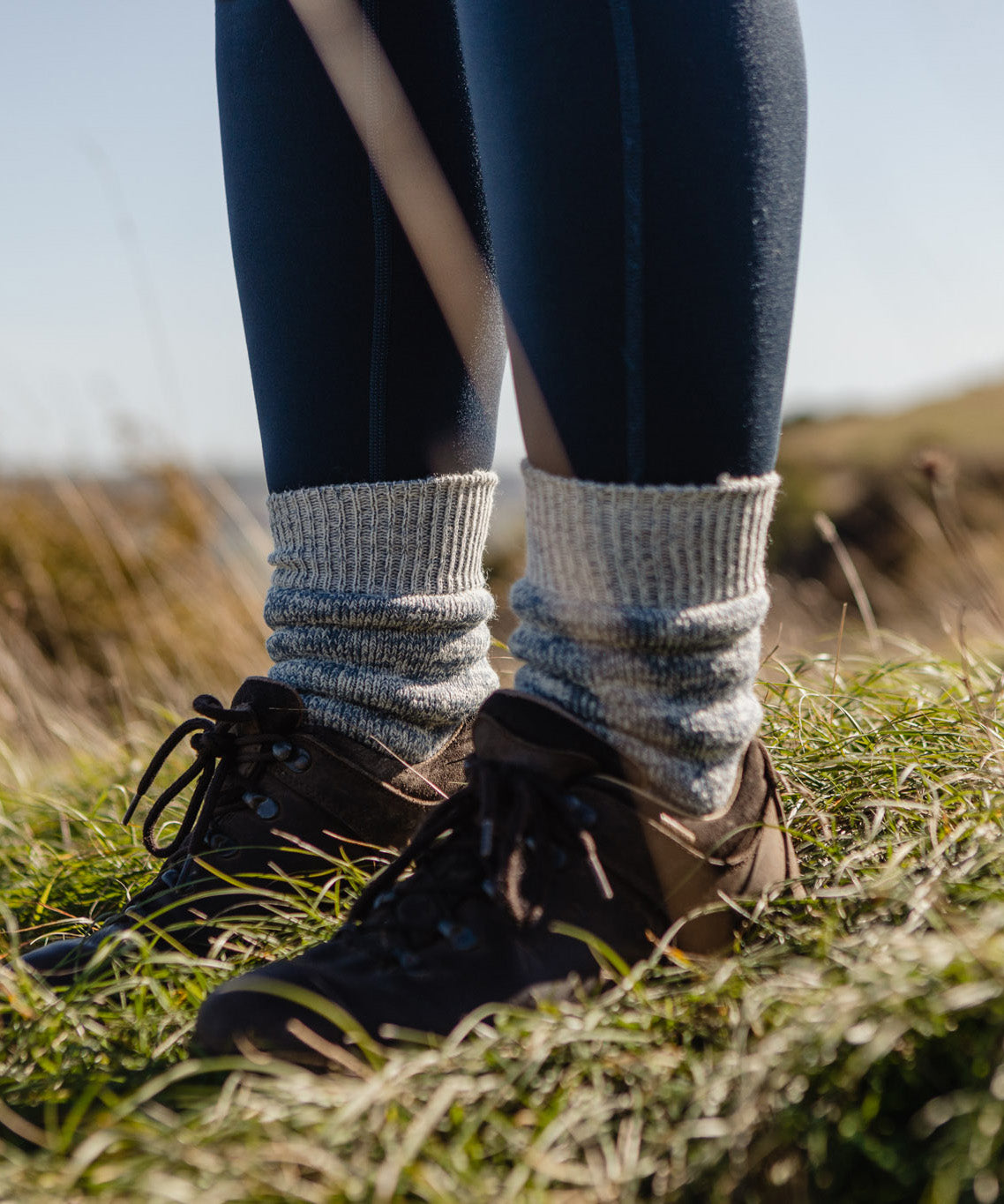 A closeup of a person wearing hiking boots and the Silverstick Happy Hiking Wool Socks in blue marl.