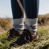 A closeup of a person wearing hiking boots and the Silverstick Happy Hiking Wool Socks in blue marl.