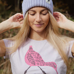 A close up of a woman wearing the Silverstick Matt Sewell Curlew Organic T-Shirt in a Lilac colour.