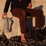 A man taking off the Silverstick wool hiking shoes after a walk, as he leans on a rock.