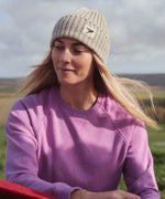 A woman on a hike, wearing the Silverstick Moffat Merino Wool beanie hat in a cream colour to keep naturally warm.