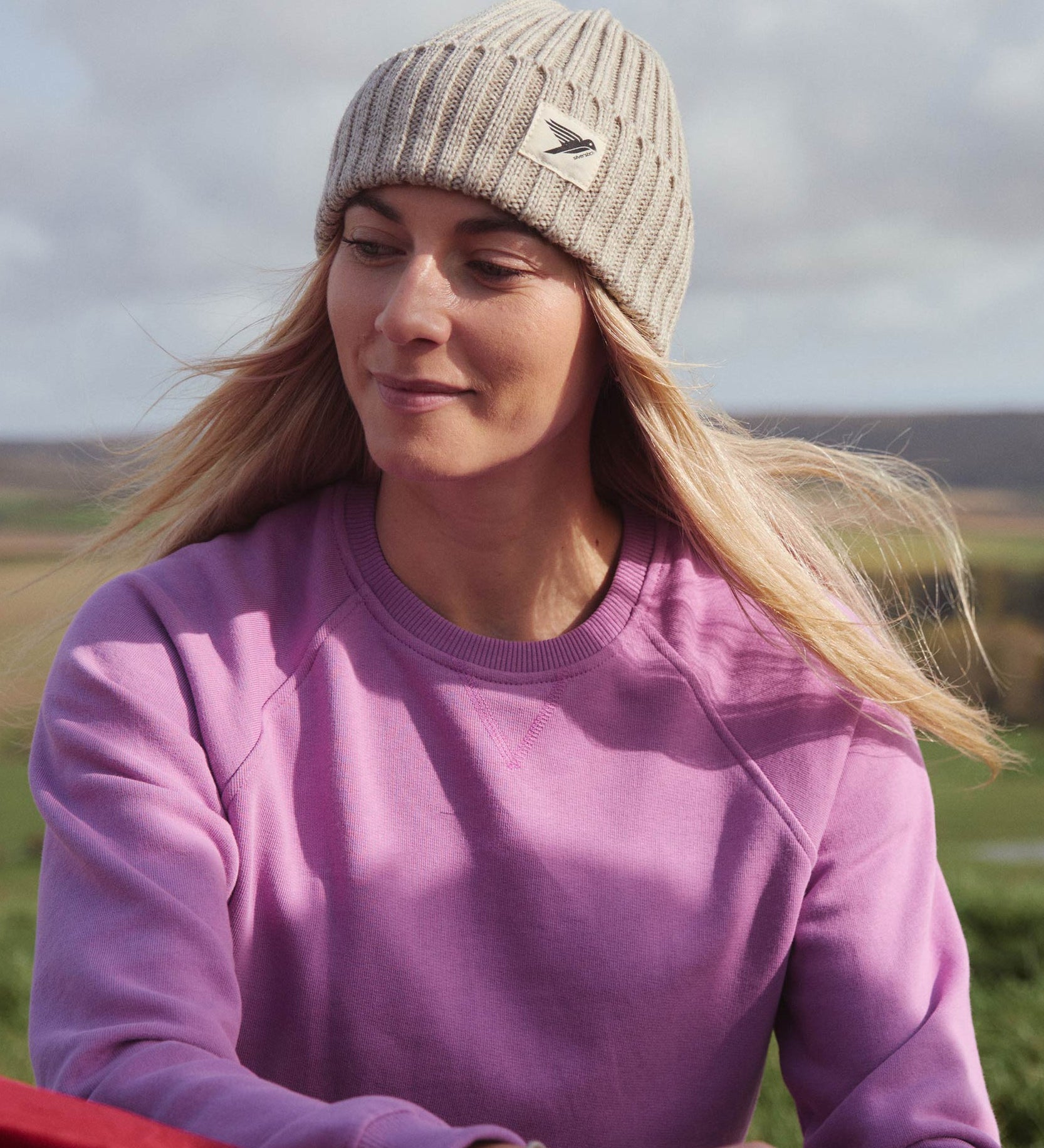 A woman on a hike, wearing the Silverstick Moffat Merino Wool beanie hat in a cream colour to keep naturally warm.