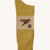 A pair of mustard yellow GOTS-Certified organic cotton everyday socks by Silverstick in recyclable paper packaging, made in Britain.