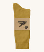 A pair of mustard yellow GOTS-Certified organic cotton everyday socks by Silverstick in recyclable paper packaging, made in Britain.