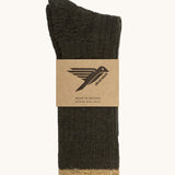 The moss green Silverstick Pennine Wool Socks shown folded over and placed in their cardboard packaging slip.