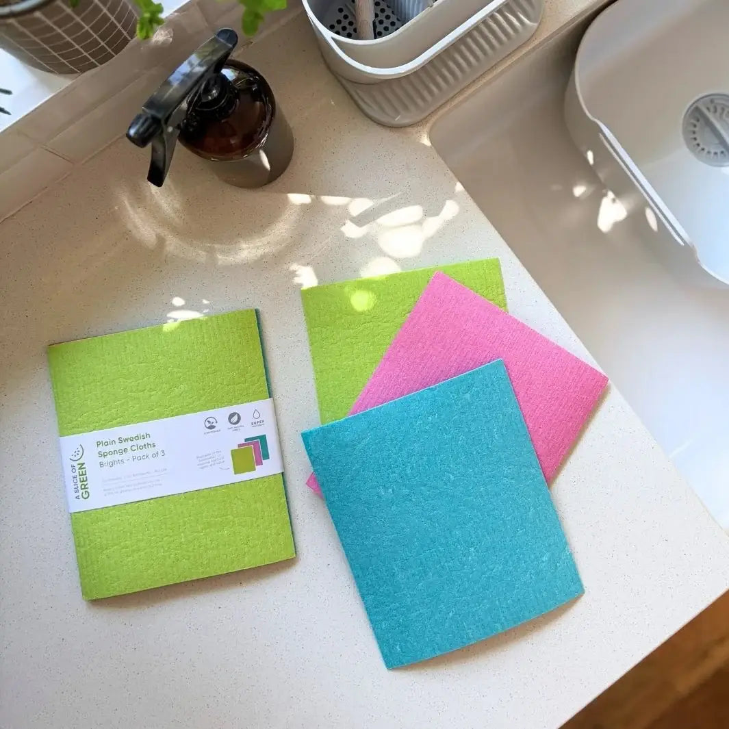A Slice of Green Brights pack of three Swedish sponge cloths, with green, pink, and blue cloths displayed in a plastic-free kitchen.