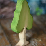 A small Ostheimer birch tree figure placed on a wooden surface. These wooden figures are part of a wide range of expertly hand crafted wooden toys here at Babipur. 