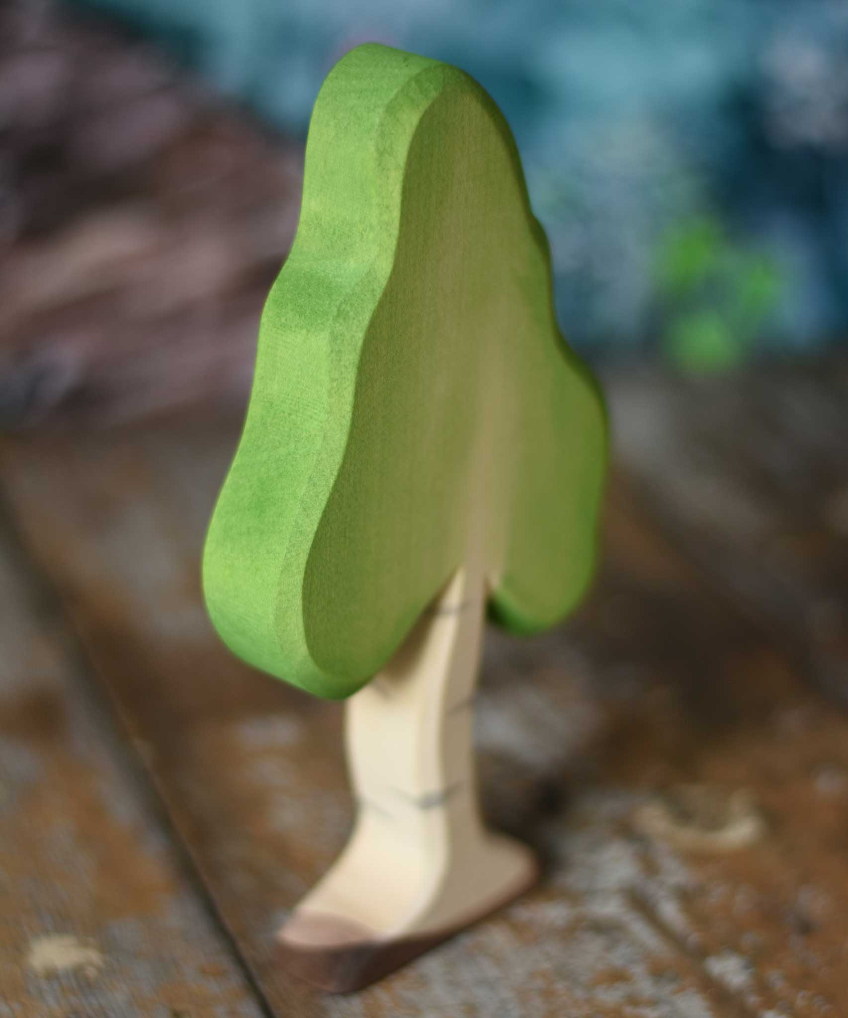 A small Ostheimer birch tree figure placed on a wooden surface. These wooden figures are part of a wide range of expertly hand crafted wooden toys here at Babipur. 