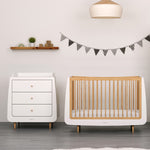A natural SnuzKot changing unit pictured next to a matching cotbed