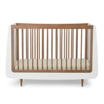 A SnuzKot Cot bed in walnut pictured on a plain background 