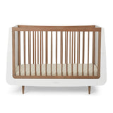 A SnuzKot Cot bed in walnut pictured on a plain background 