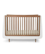 A SnuzKot Cot bed in walnut pictured on a plain background 