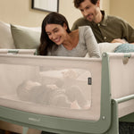 Two parents loving view their baby in the SnuzPod5 bedside crib, watching the baby from the comfort of their own bed.