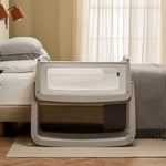 The SnuzPod 5 bedside baby crib with a lovely light grey wooden frame, next to an adult's bed in a beautifully decorated bedroom.