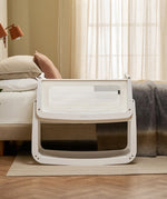 The SnuzPod 5 bedside baby crib with a lovely white wooden frame, next to an adult's bed in a beautifully decorated bedroom.