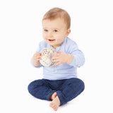 A baby playing with The Sophie the Giraffe natural Hevea rubber teething ball toy or babies, with non-toxic paints and textured elements. 