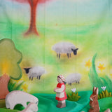 Children's play cloth with sheep, a shepherd, and a rabbit in a colorful landscape.