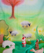 Children's play cloth with sheep, a shepherd, and a rabbit in a colorful landscape.