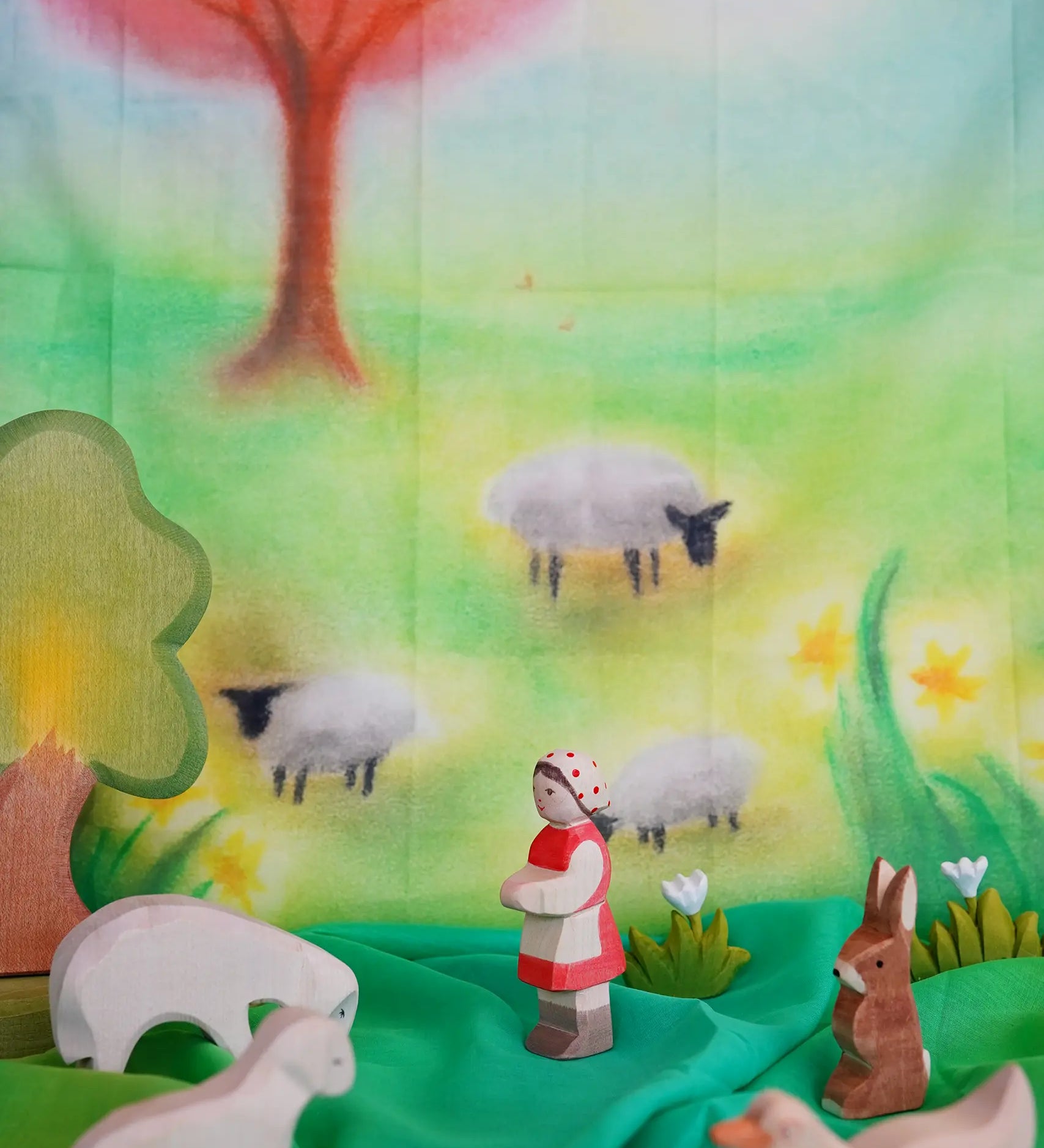 Children's play cloth with sheep, a shepherd, and a rabbit in a colorful landscape.
