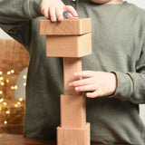 A close up of a child playing with the Bajo Square Pyramid Sensory Wooden Stacking Toy. The child is stacking the pieces in a random order. The set contains 5 wooden square and rectangular shaped blocks with a different coloured bases. Each blocks make a different sound when shaken. These heirloom quality toys by Bajo are part of a wide range of wooden toys available here at Babipur. 