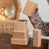 A close up of a child playing with the Bajo Square Pyramid Sensory Wooden Stacking Toy. The set contains 5 wooden square and rectangular shaped blocks with a different coloured bases. Each blocks make a different sound when shaken. These heirloom quality toys by Bajo are part of a wide range of wooden toys available here at Babipur. 