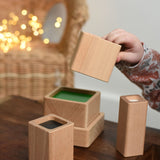 A close up of a child playing with the Bajo Square Pyramid Sensory Wooden Stacking Toy. The set contains 5 wooden square and rectangular shaped blocks with a different coloured bases. Each blocks make a different sound when shaken. These heirloom quality toys by Bajo are part of a wide range of wooden toys available here at Babipur. 