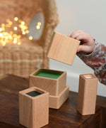 A close up of a child playing with the Bajo Square Pyramid Sensory Wooden Stacking Toy. The set contains 5 wooden square and rectangular shaped blocks with a different coloured bases. Each blocks make a different sound when shaken. These heirloom quality toys by Bajo are part of a wide range of wooden toys available here at Babipur. 