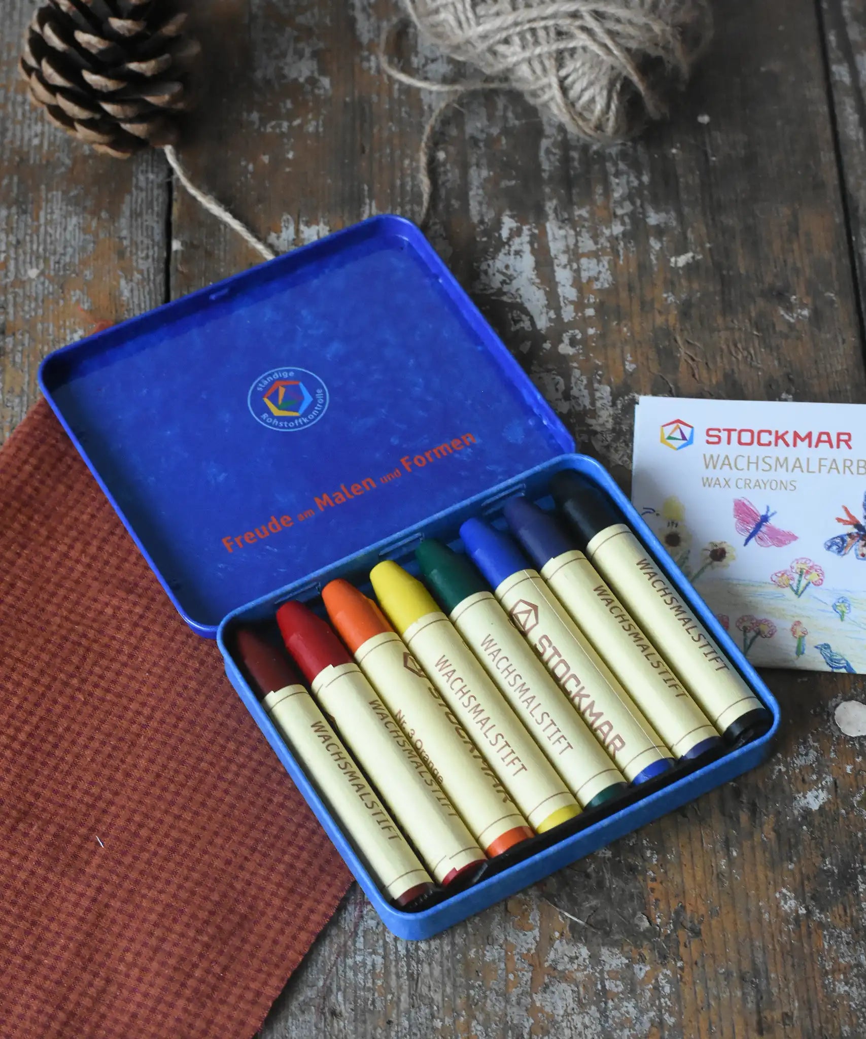 Stockmar 8 Standard Colour assortment Wax Crayons in a tin. Carmine red, orange, lemon yellow, green, blue violet, rust and black coloured wax crayon sticks.