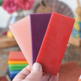 pink, purple and red Stockmar Modelling Beeswax Clay Sheets in an adult's hand. 