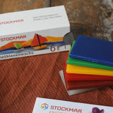 Stockmar modelling beeswax in a pack of 6 Sheets. White, brown, red, yellow green and blue sheets shown out of the cardboard box.