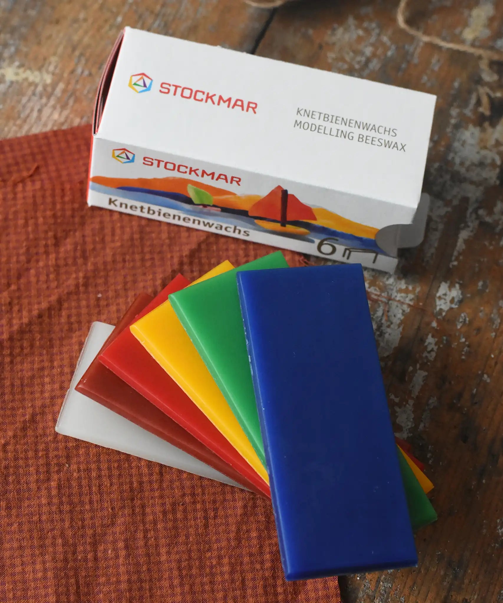 Stockmar modelling beeswax in a pack of 6 Sheets. White, brown, red, yellow green and blue sheets shown outside the cardboard box.