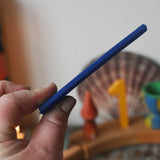 Blue Stockmar modelling beeswax sheet in an adult's hand showing thickness. 