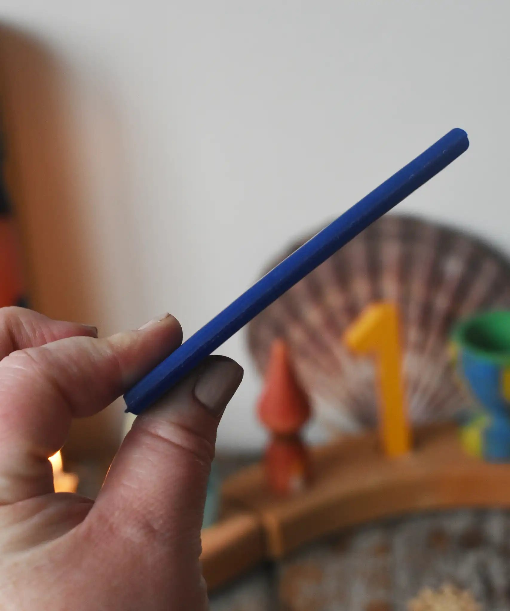 Blue Stockmar modelling beeswax sheet in an adult's hand showing thickness. 