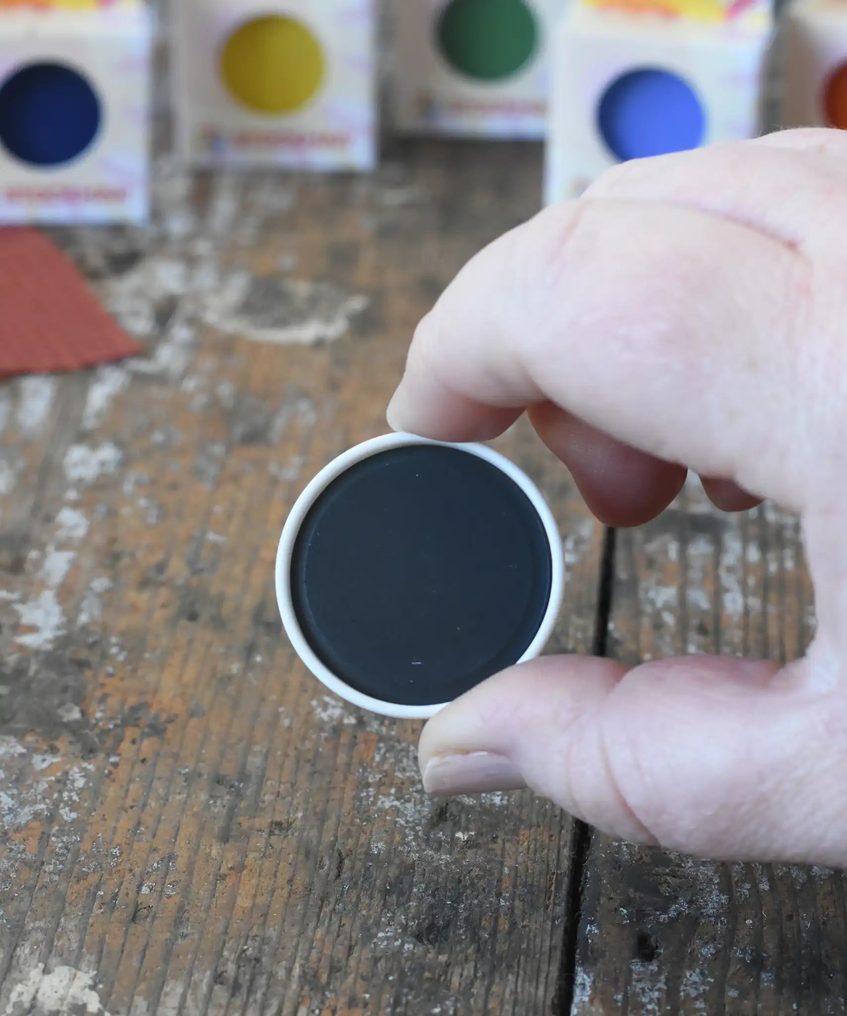 Stockmar black opaque watercolour replacement tablet in an adult's hand.