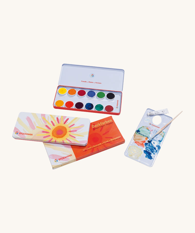 Stockmar Opaque Watercolour Tin Set. 12 colour paint pans in a metal tin with a tube of opaque white along with a brush and mixing pallete.
